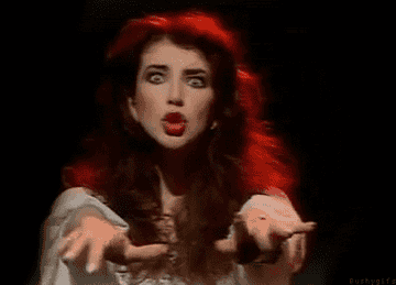 Kate Bush performing live and looking around and wiggling her fingers