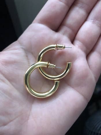 reviewer holding the thick gold hoops