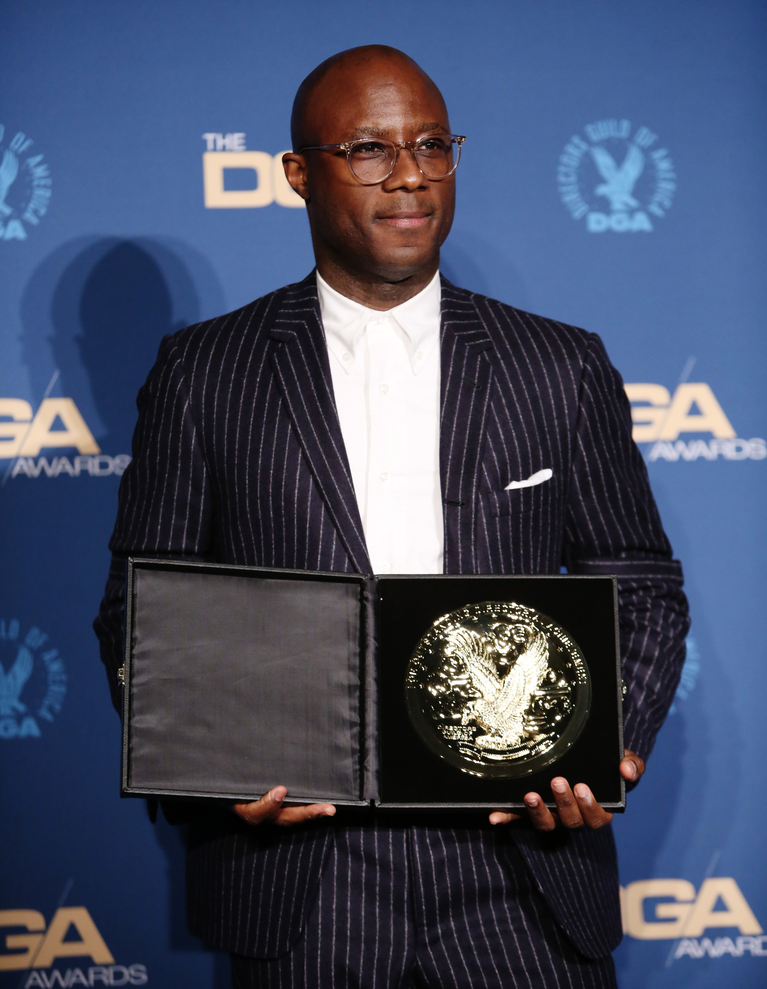 barry jenkins poses with an award