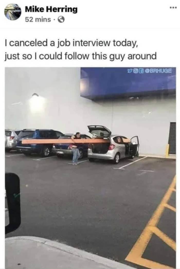 person trying to fit a plank of wood in car