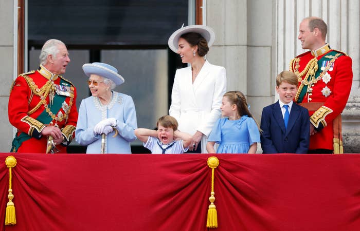 The royal family smiling while Louis holds his hands over his ears and screams