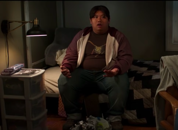 Jacob Batalon sitting on a bed with his mouth open in shock