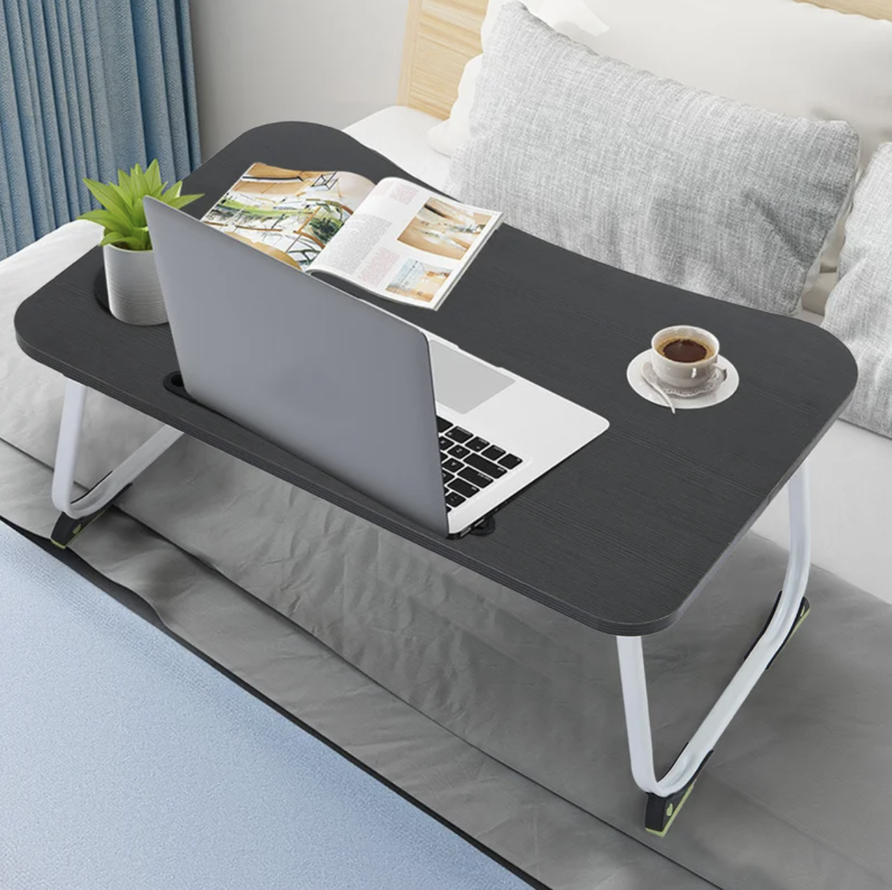 the foldable bed tray holding a laptop and a cup of coffee
