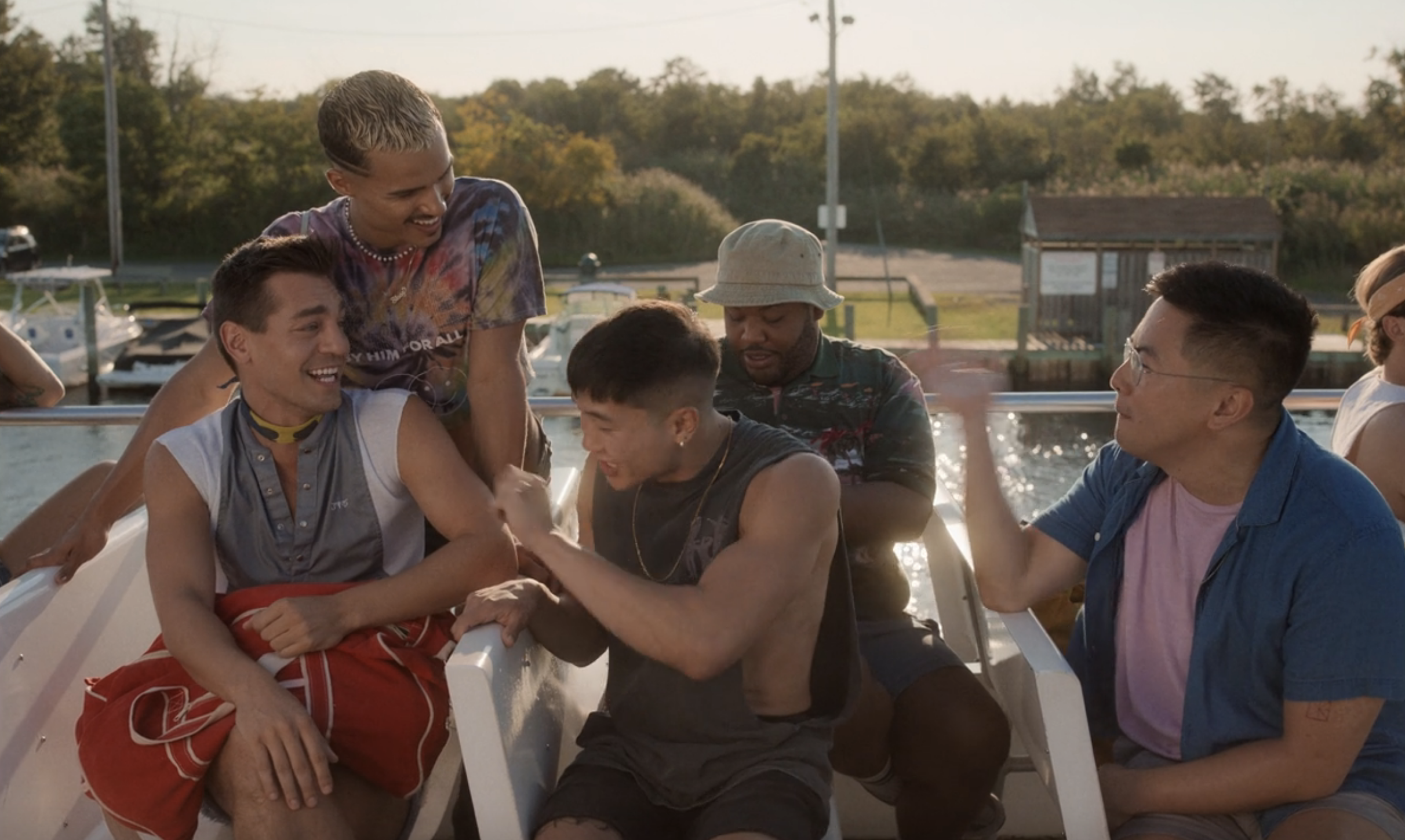Men sitting together by a body of water and laughing