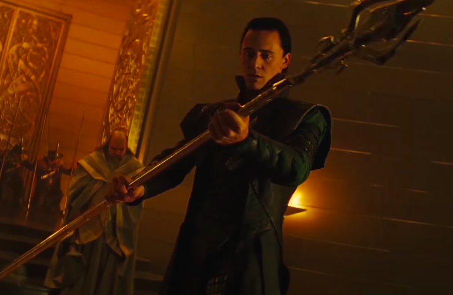 Tom Hiddleston as Loki holding a large weapon