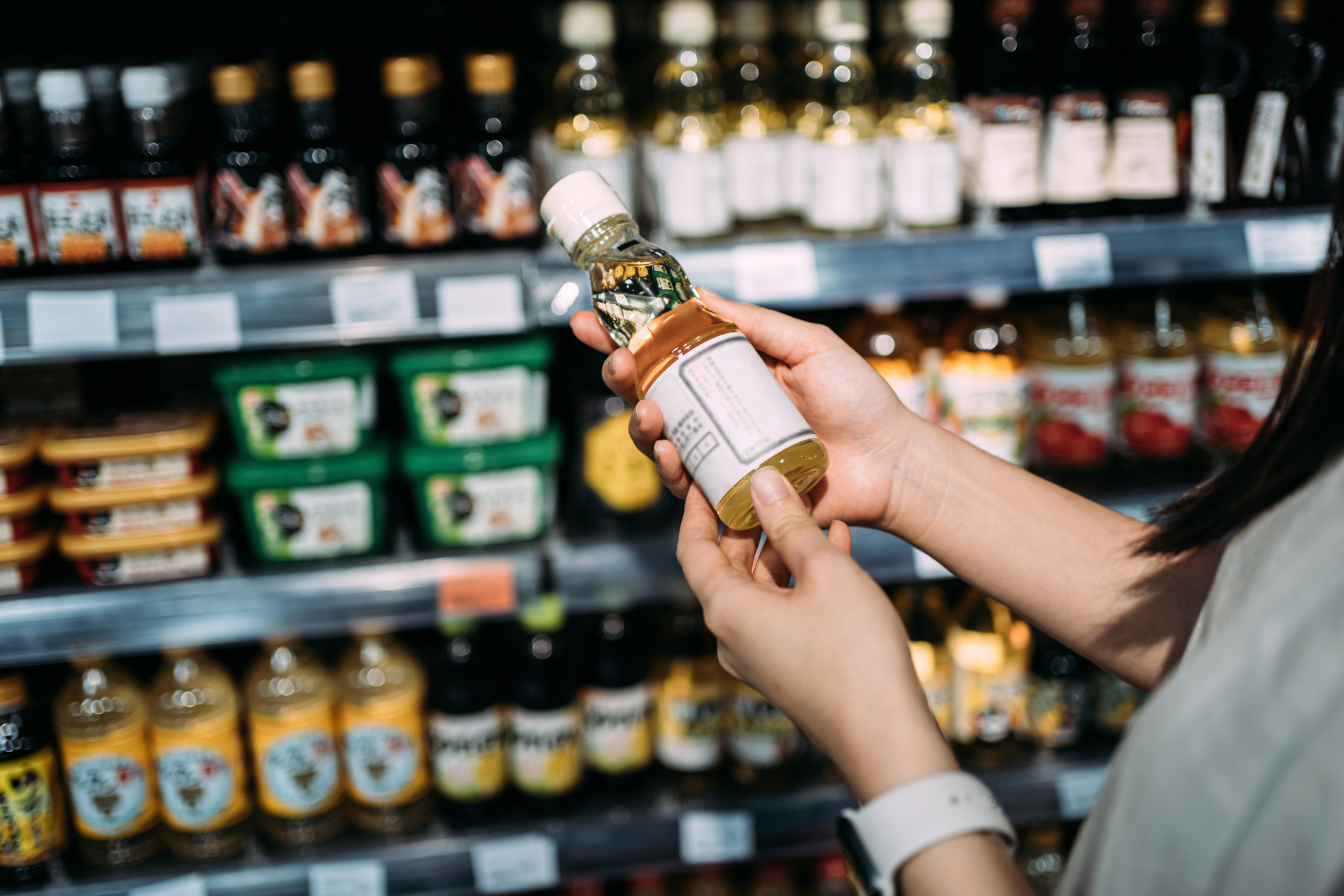 A woman holding a bottle of vinegar in a market.