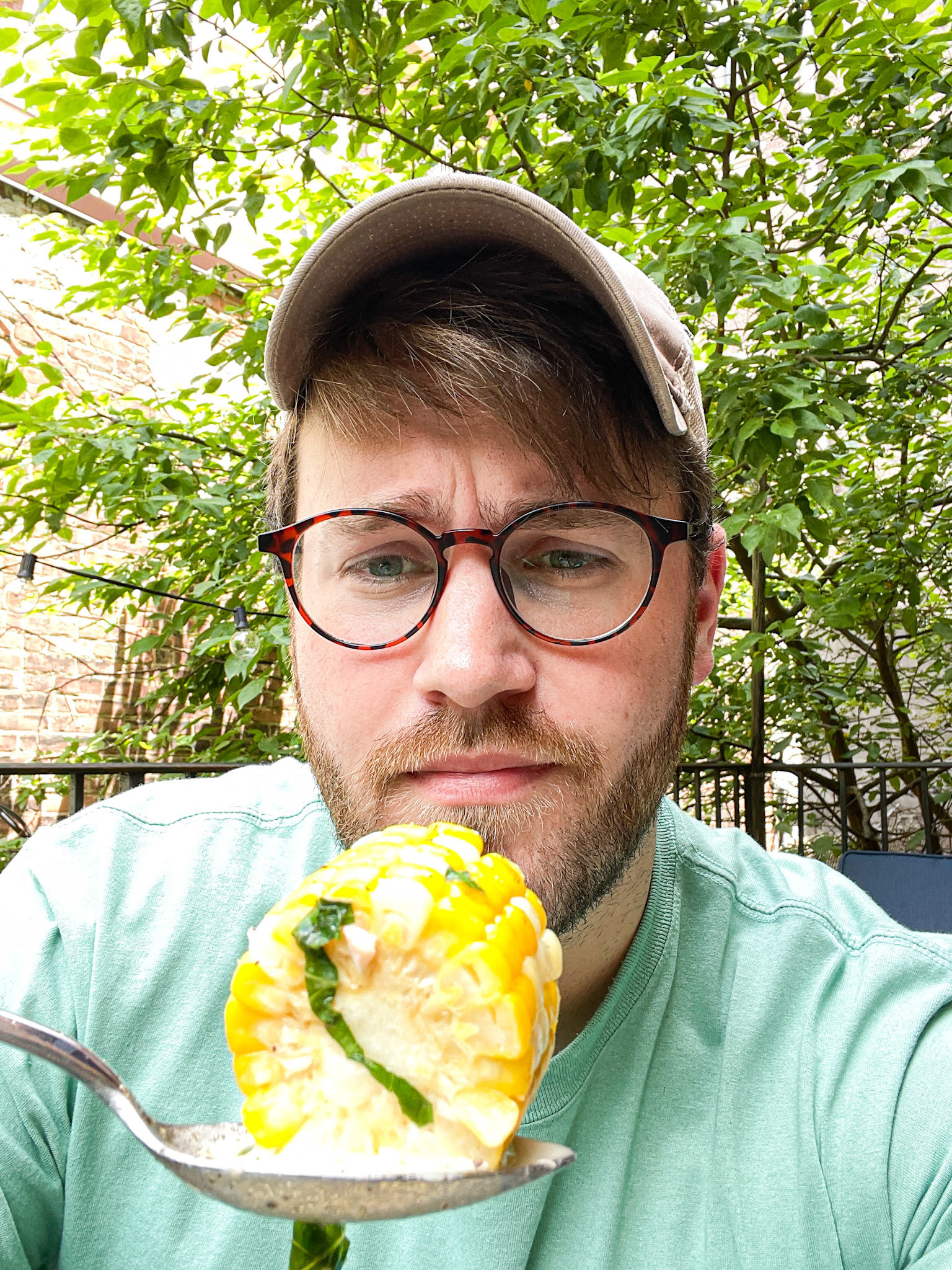 The writer looking sad as he picks up a big piece of soup-soaked corn with his spoon