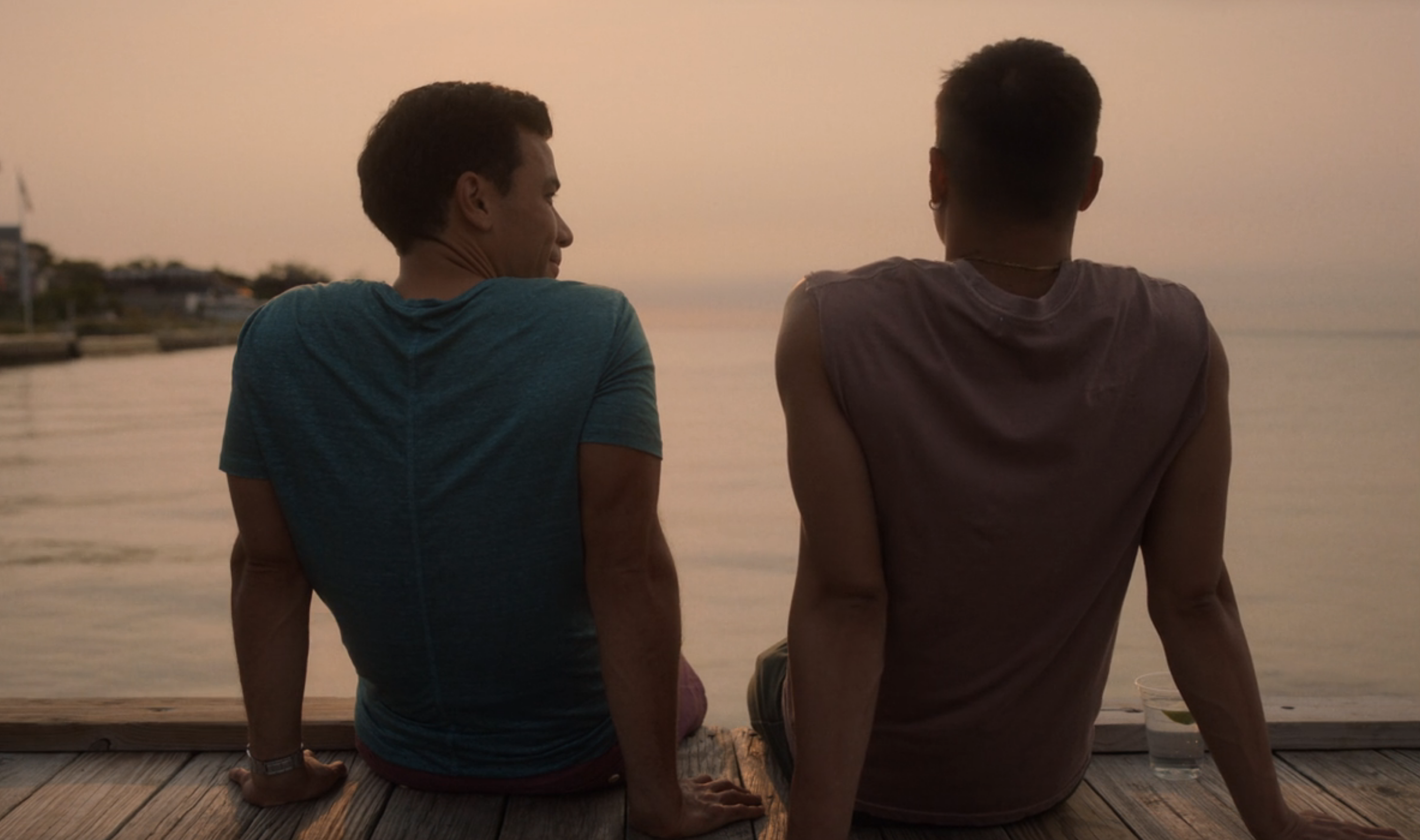 A back shot of Ricamora and Booster sitting by the water talking