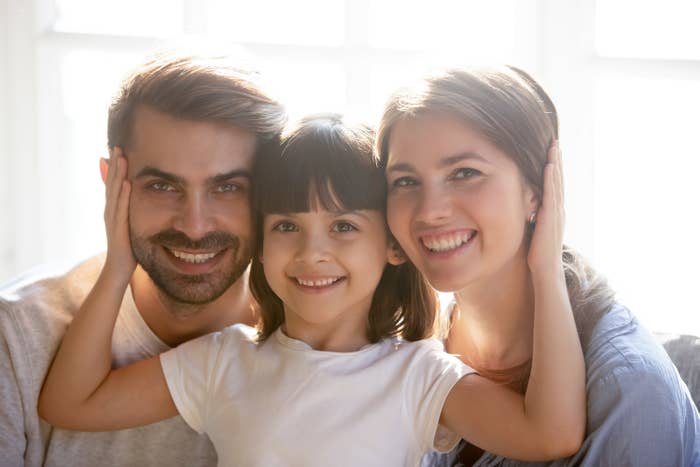 A couple smiles with their young daughter