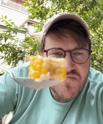 The writer struggling to eat corn on the cob with a spoon