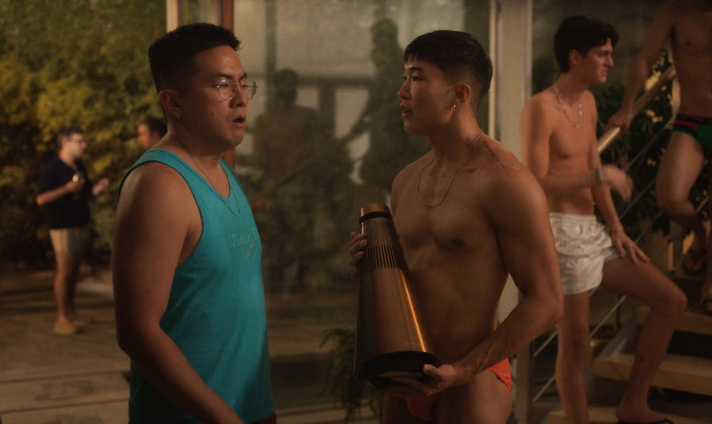 Men in briefs, trunks, and shirts standing around together talking