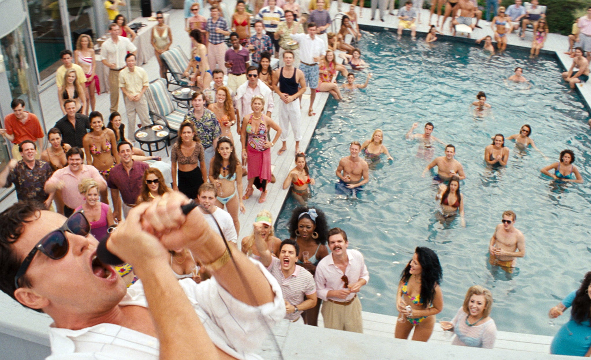 Leonardo DiCaprio shouts into a microphone at a pool party