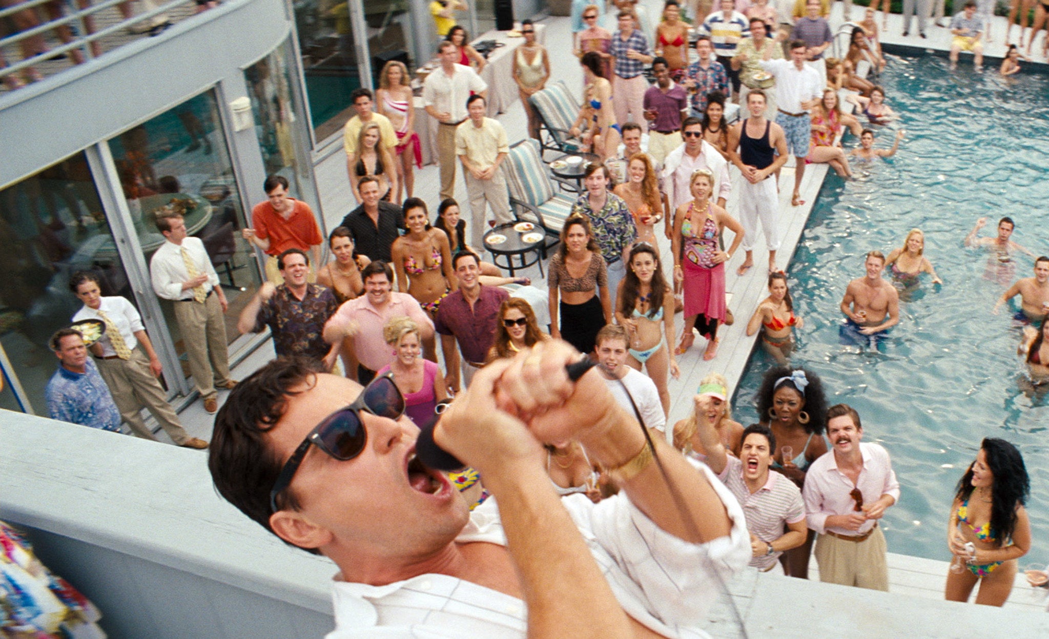 Leonardo DiCaprio shouts into a microphone at a pool party