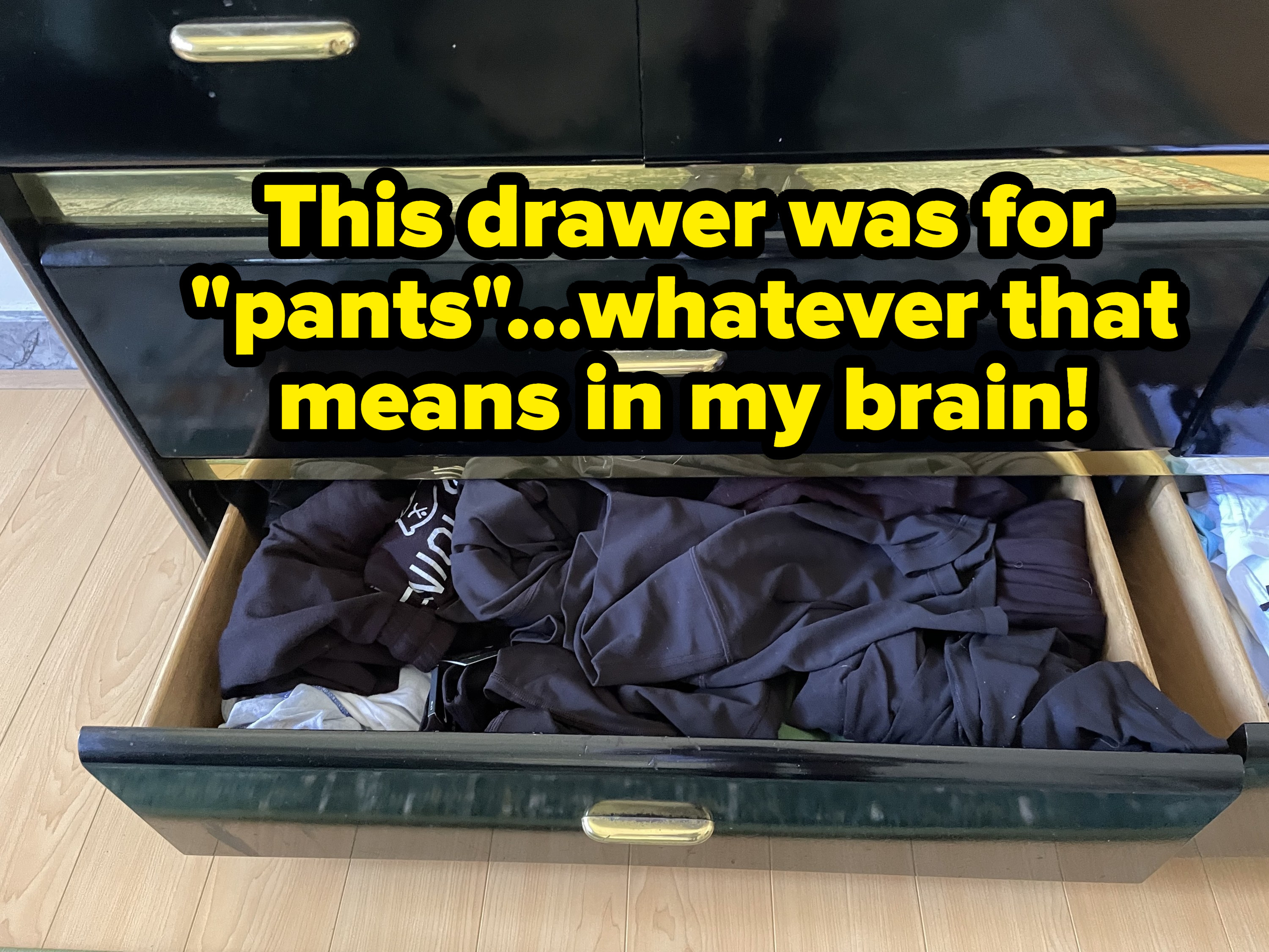 A bunch of dark-colored pants seemingly shoved into a drawer at random