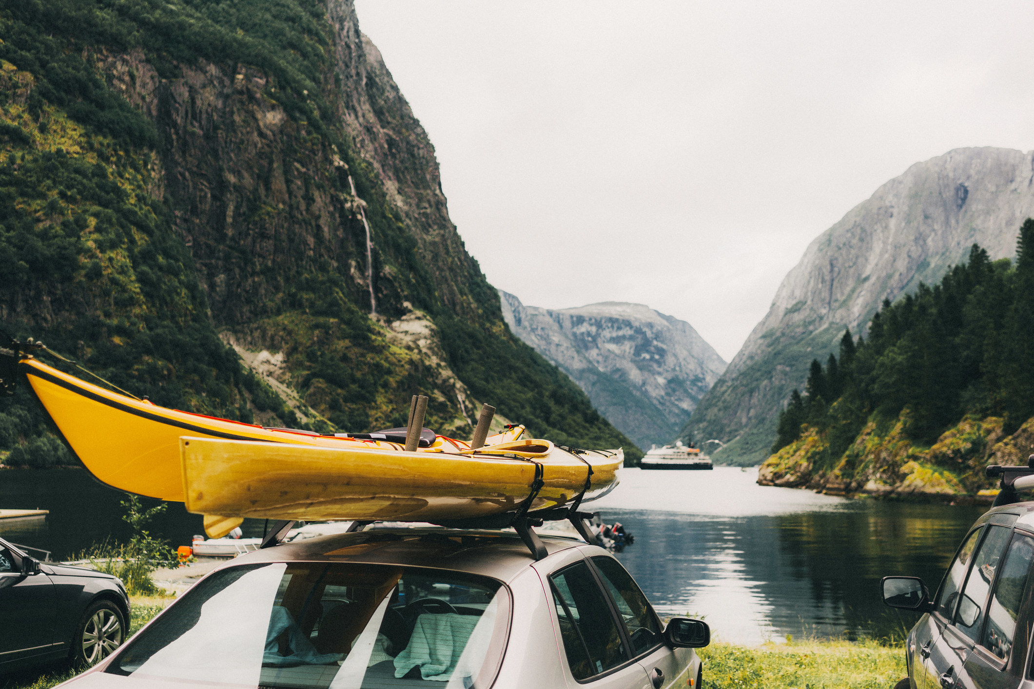 A kayak sits on top of a car overlooking a lake