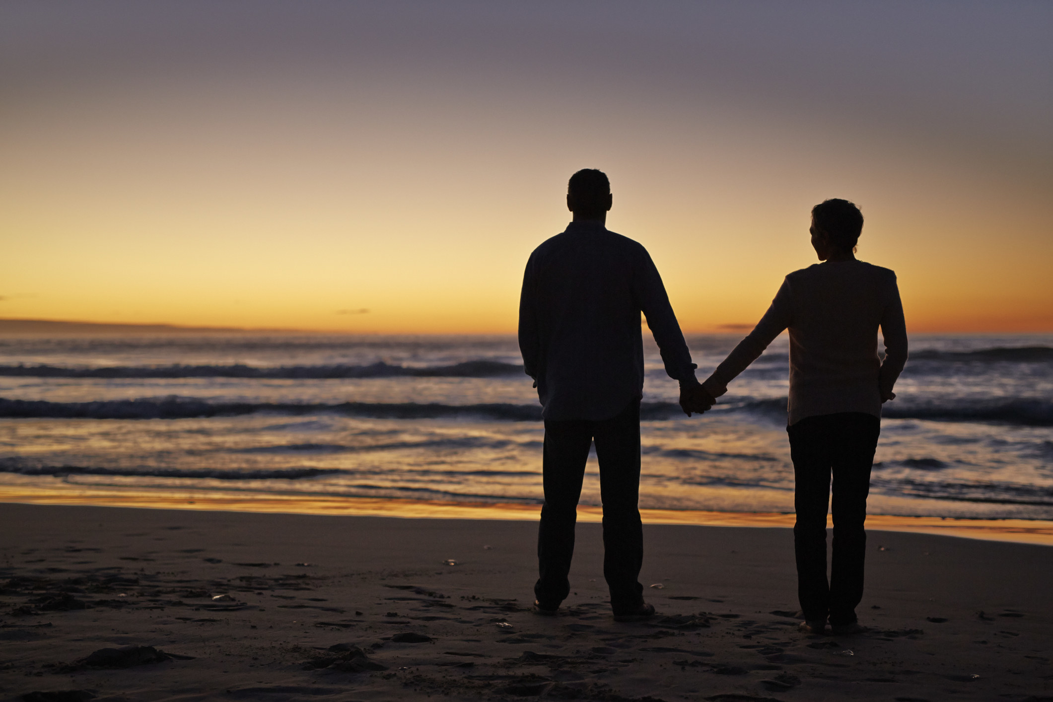 A couple holds hands by the beach