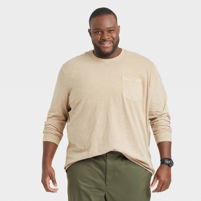 A model wears the light brown long sleeve shirt with green bottoms