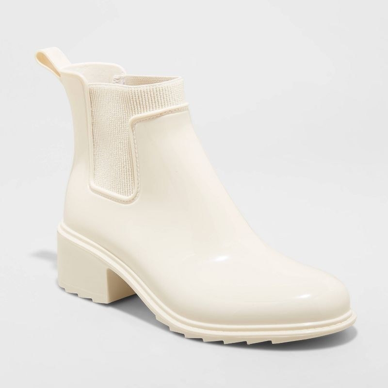The white shiny rain boots have a flocked outsole and thick chunky heel