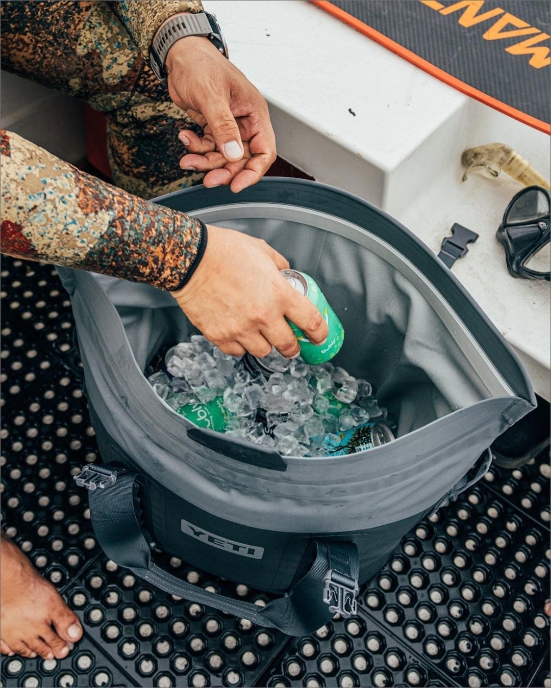 A person adding a can off pop to the cooler filled with ice