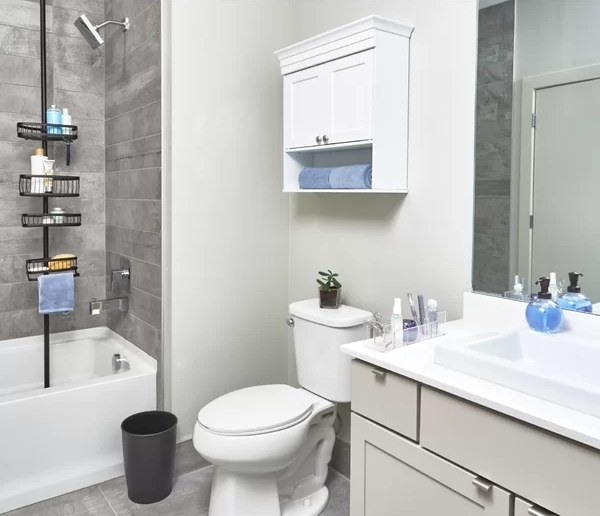 An image of a bathroom essentials kit that includes one shower pole caddy, one cosmetic organizer, one glass pump soap dispenser, and one rose waste basket