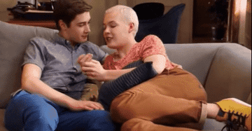 GIF two men cuddling on a couch and talking