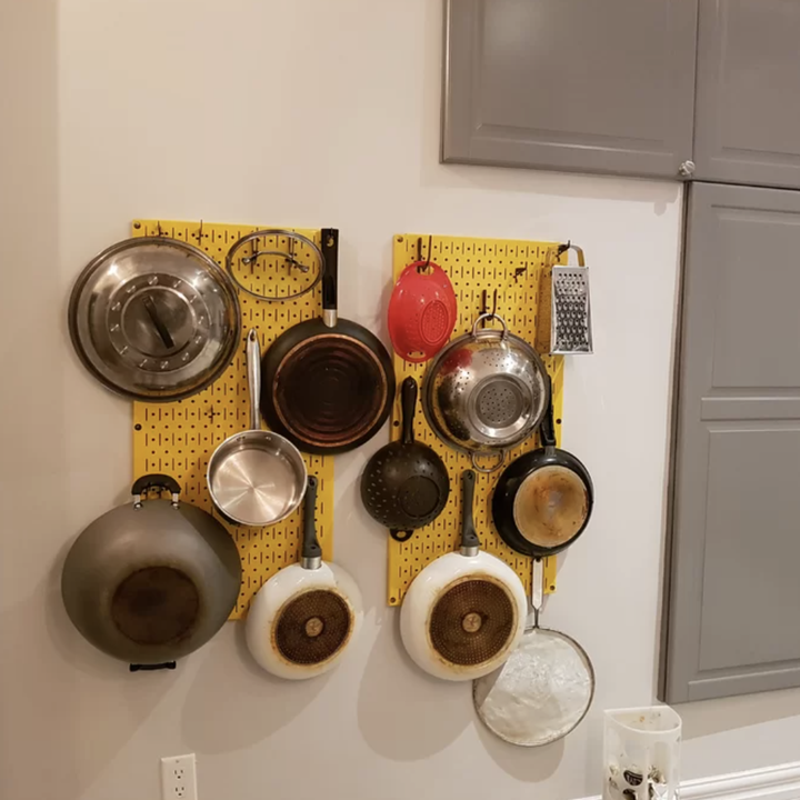 reviewer photo of the yellow pan rack on a wall holding pans