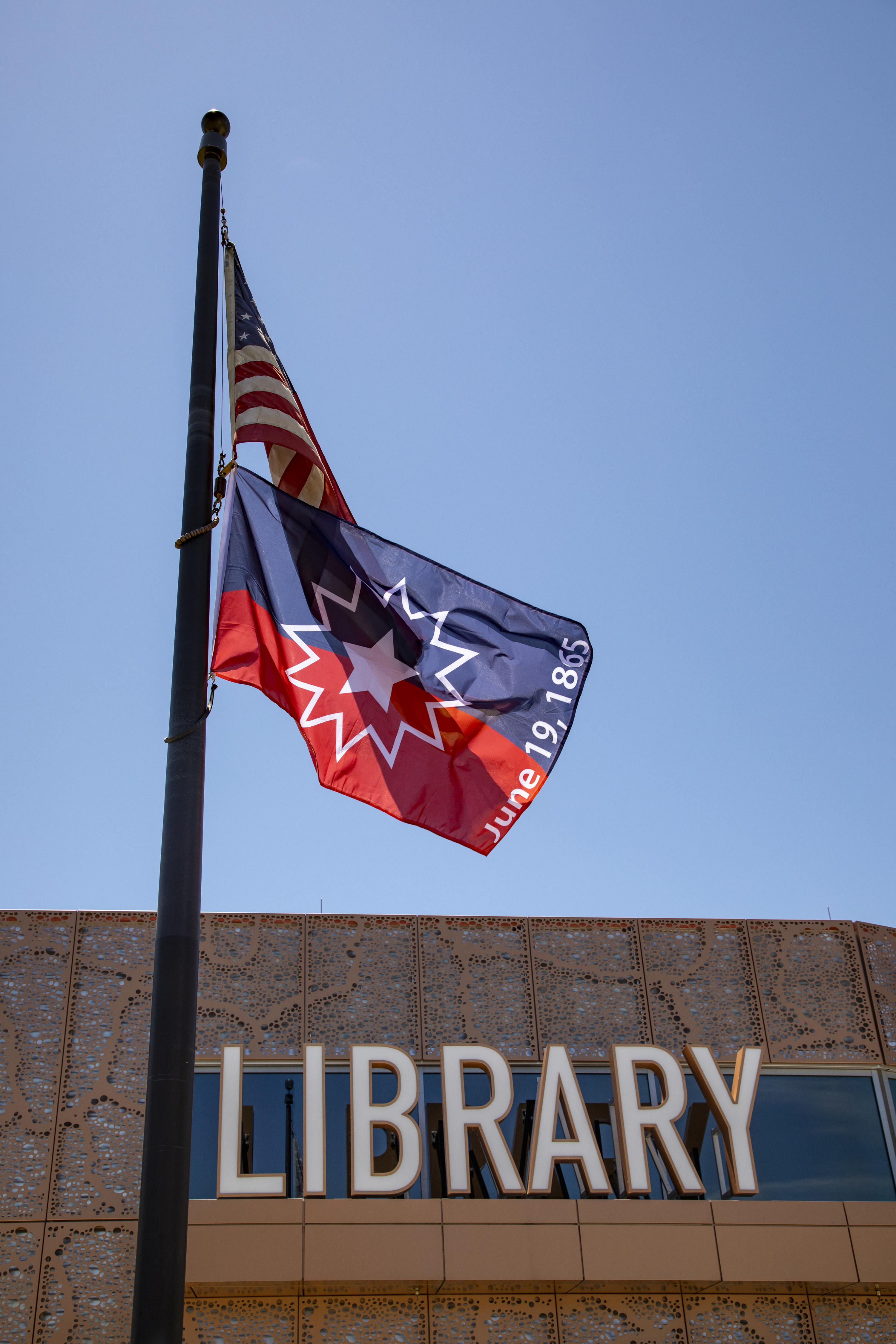 A Juneteenth flag flying over a library