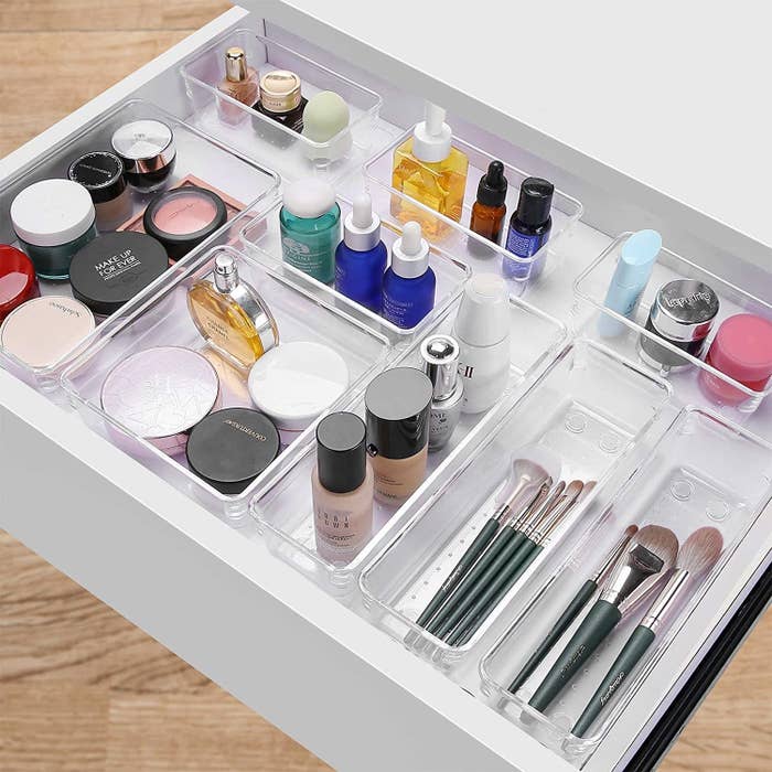 Several trays in a desk drawer with makeup in them