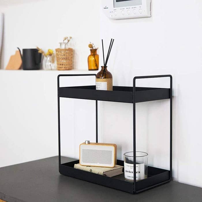 The rack with a candle, diffuser, and a speaker on it
