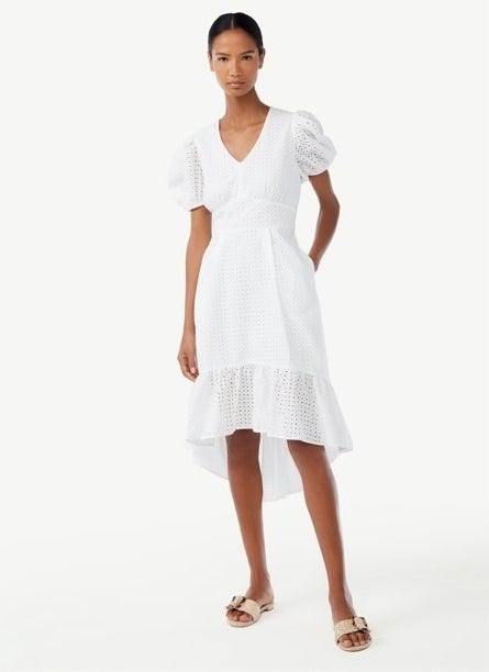 Model wearing white puffed-sleeve mini dress with high-low hem