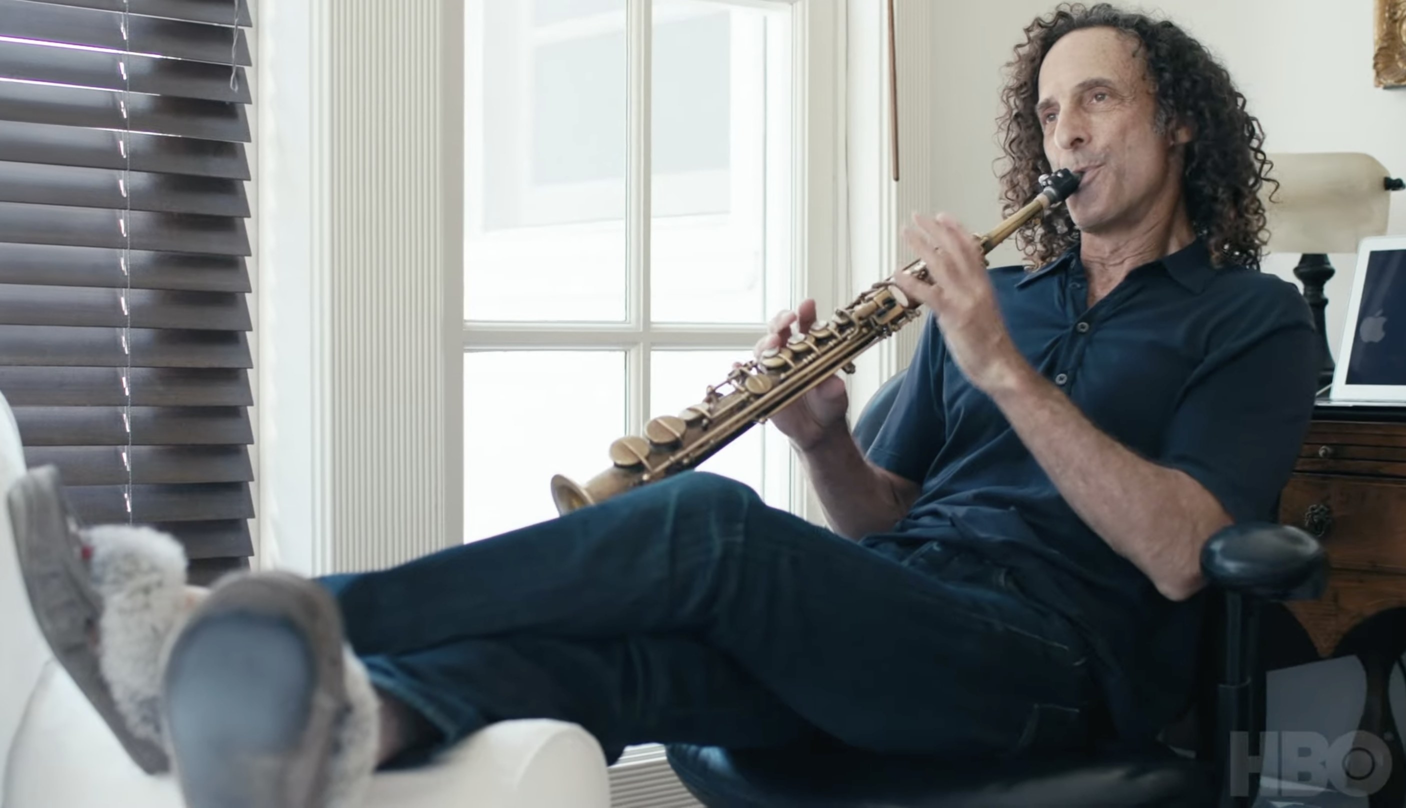 kenny g playing tenor sax in an office chair wearing slippers in &quot;listening to kenny g&quot;