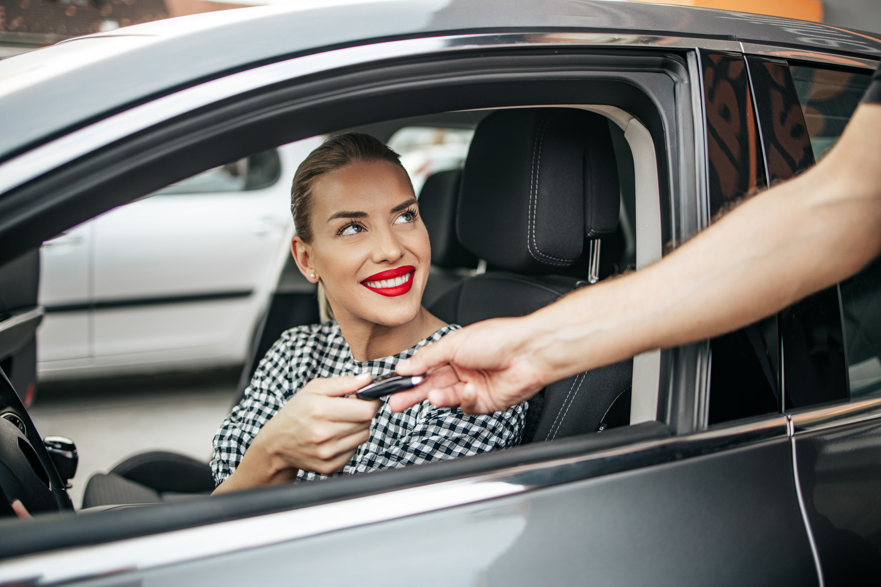 Person hands the keys to a woman in a rental car