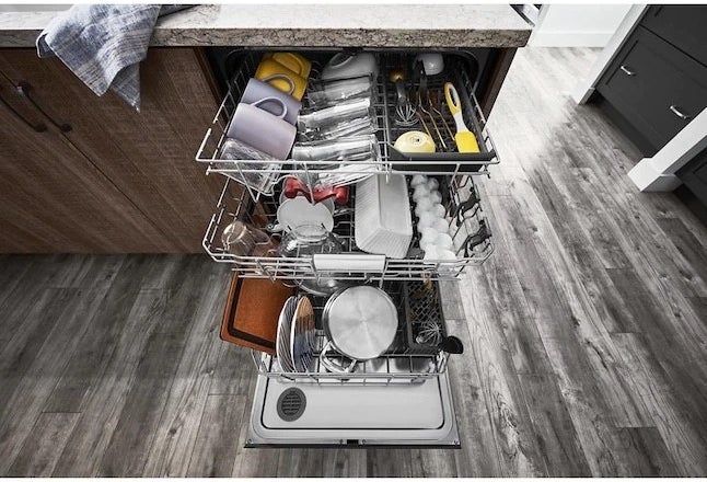 the dishwasher shown with its three racks pulled out and dishes inside