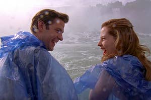 Jim and Pam from The Office wearing ponchos near a water fall and smiling at each other