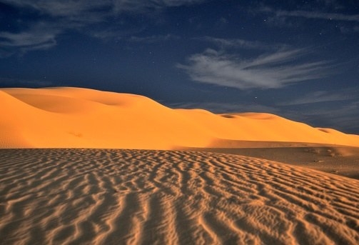 Golden dunes below a dark blue sky