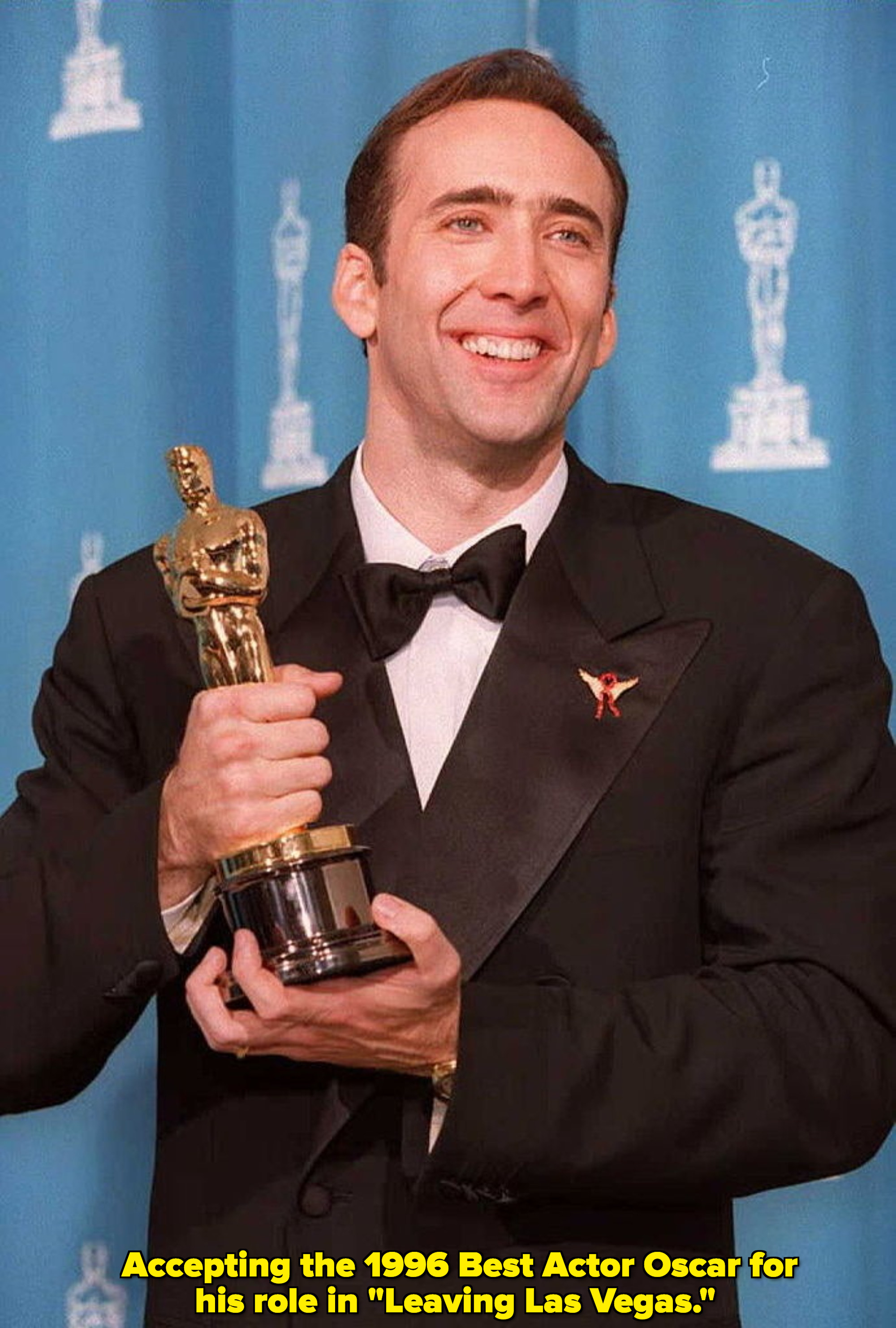 Nicolas Cage smiles and holds up an Oscar
