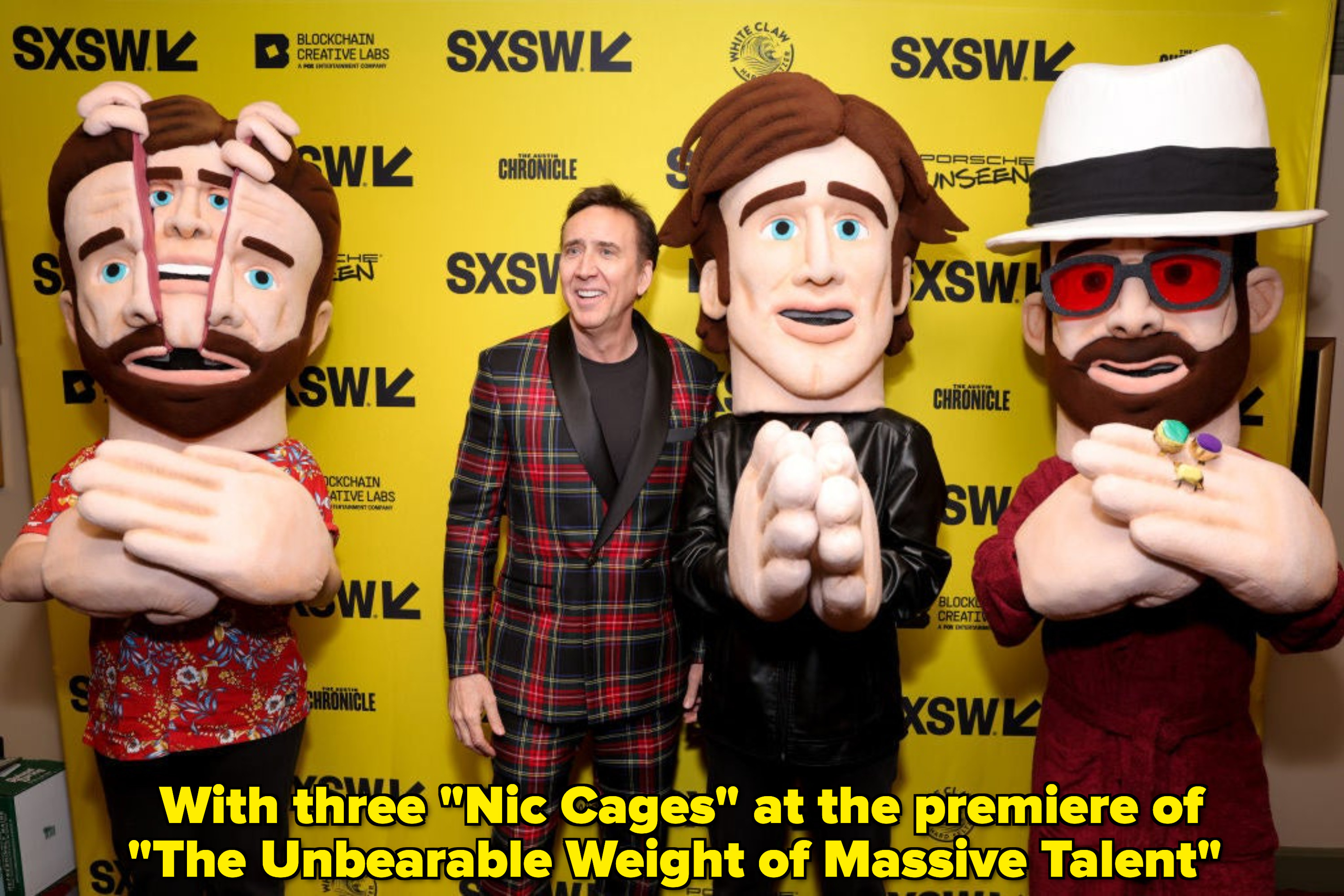 Three cartoon statues of Nic Cage and him standing next to them at SXSW