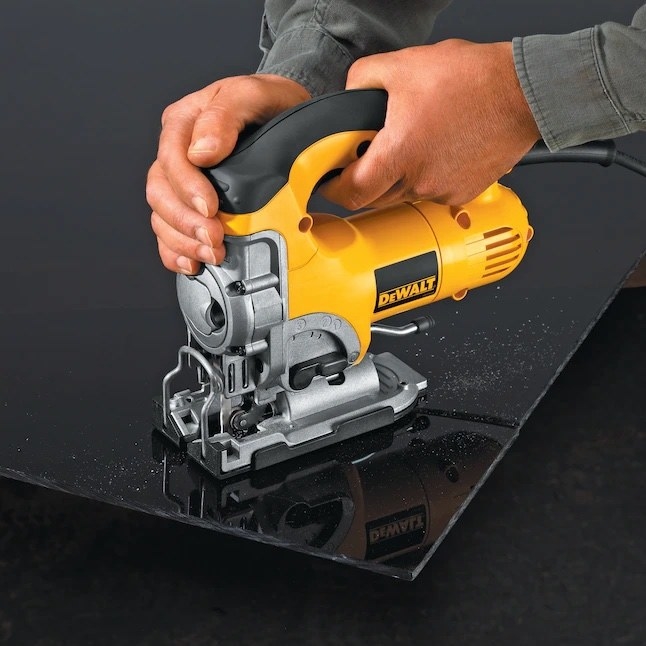 a person using a yellow and black jigsaw to cut though material