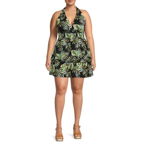 Model wearing short black halter dress with green tropical flower design