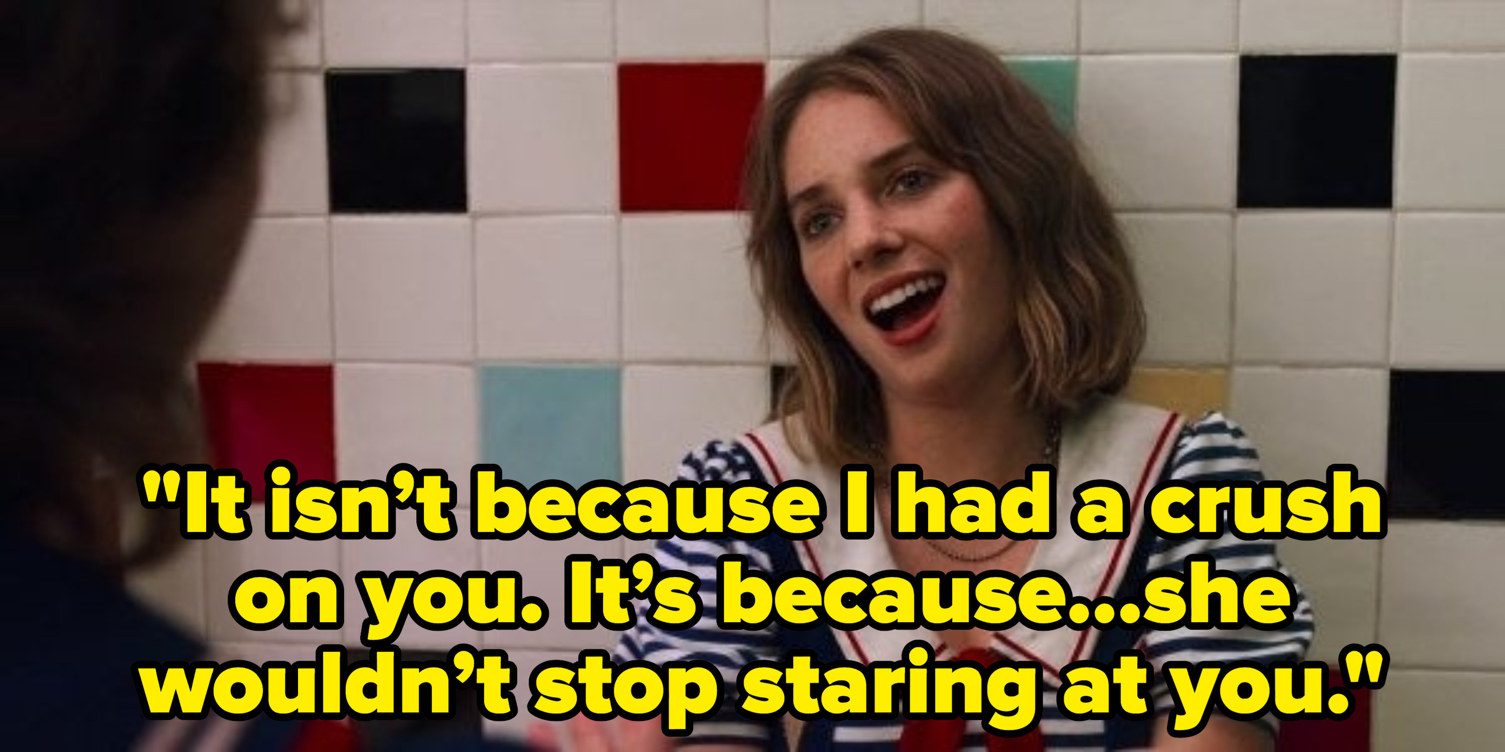 A girl, sitting against a tiled wall, speaks to someone