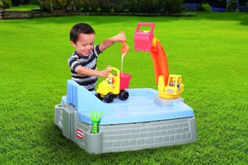 A child model playing with the construction themed sandbox