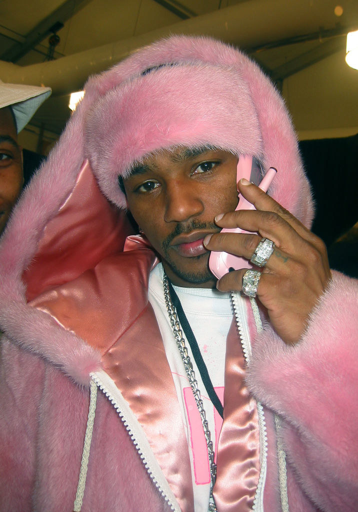 cam&#x27;ron wearing a fluffy pink hoodie holding a flip phone