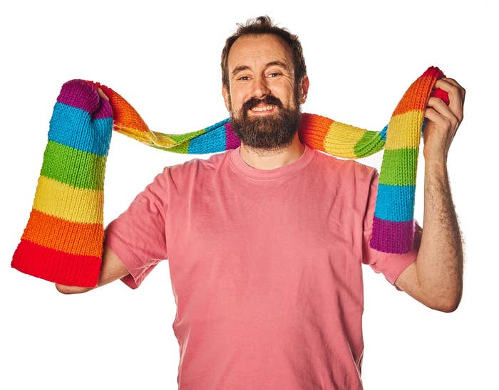 A man wrapping a Pride scarf around his neck