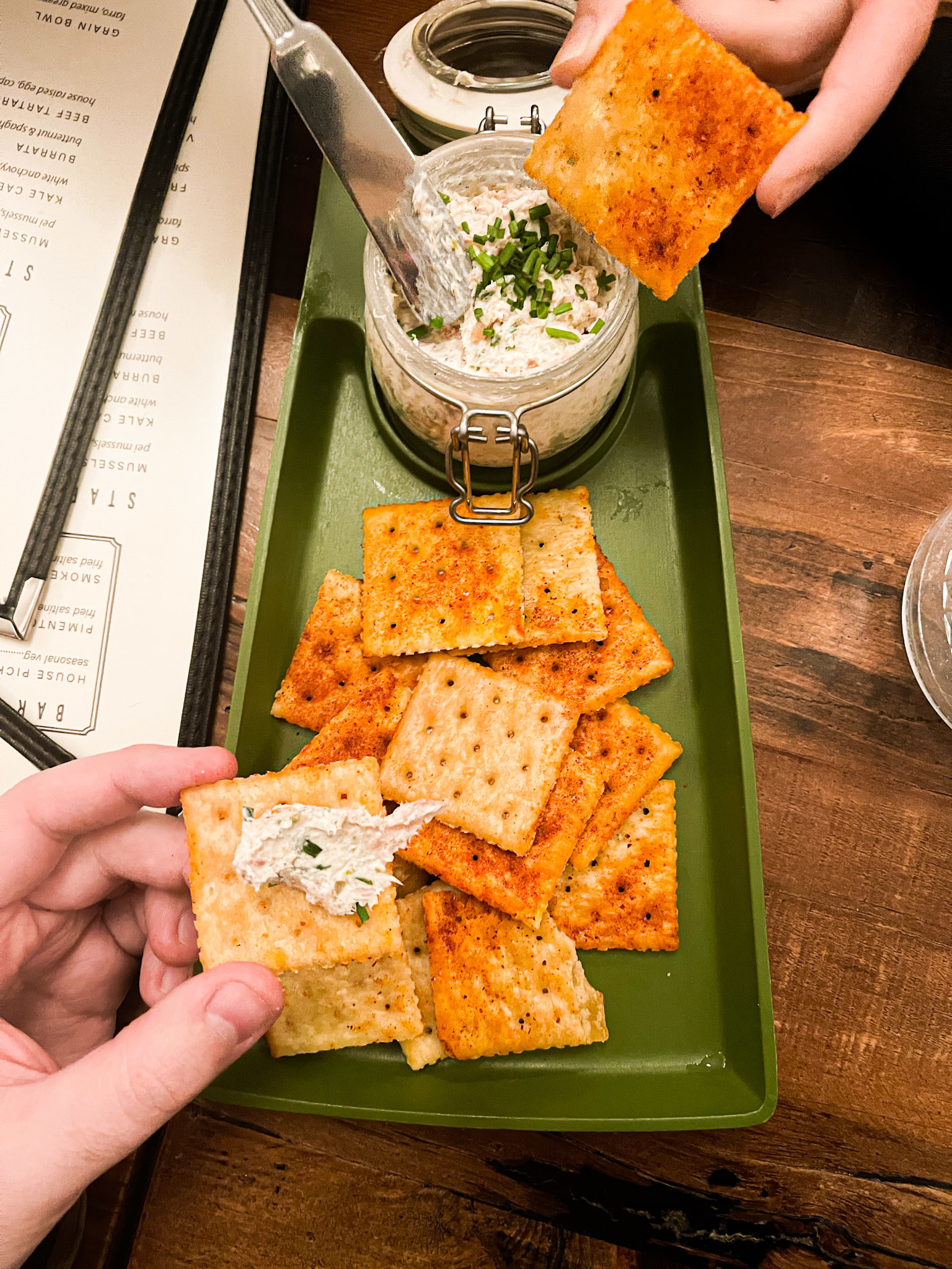 Person putting a spread on fried saltines