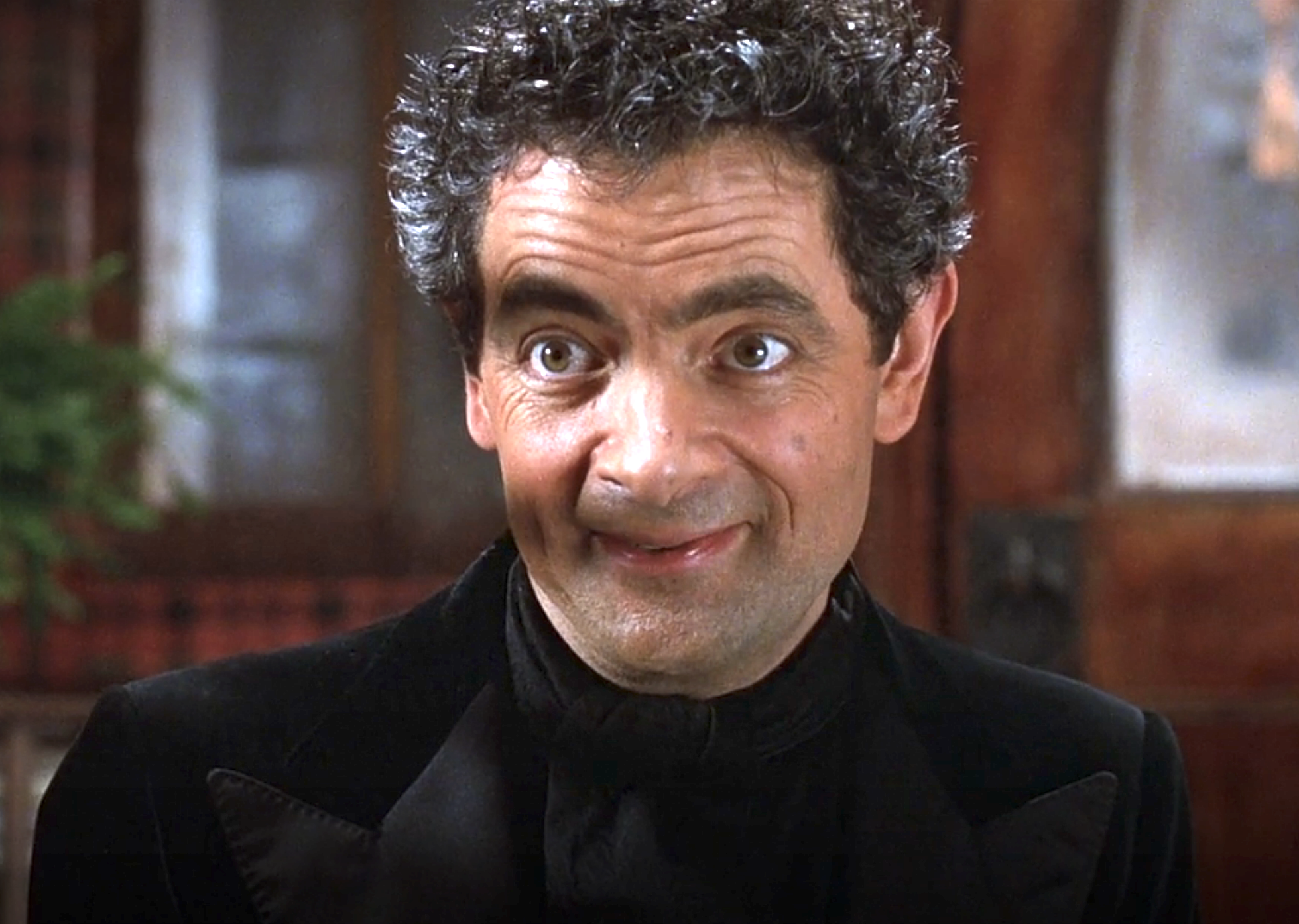 Rowan Atkinson as Mondavarious with curly hair looking sinister