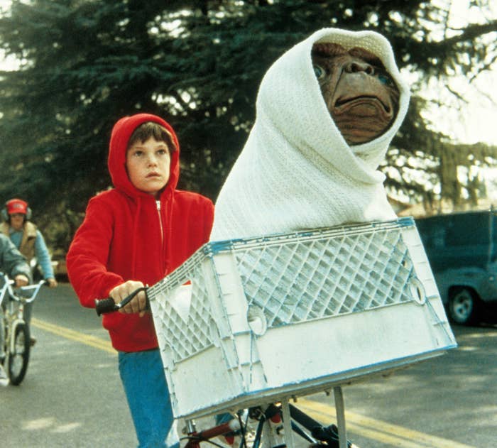 Elliot riding his bike with ET in the basket wrapped in a blanket