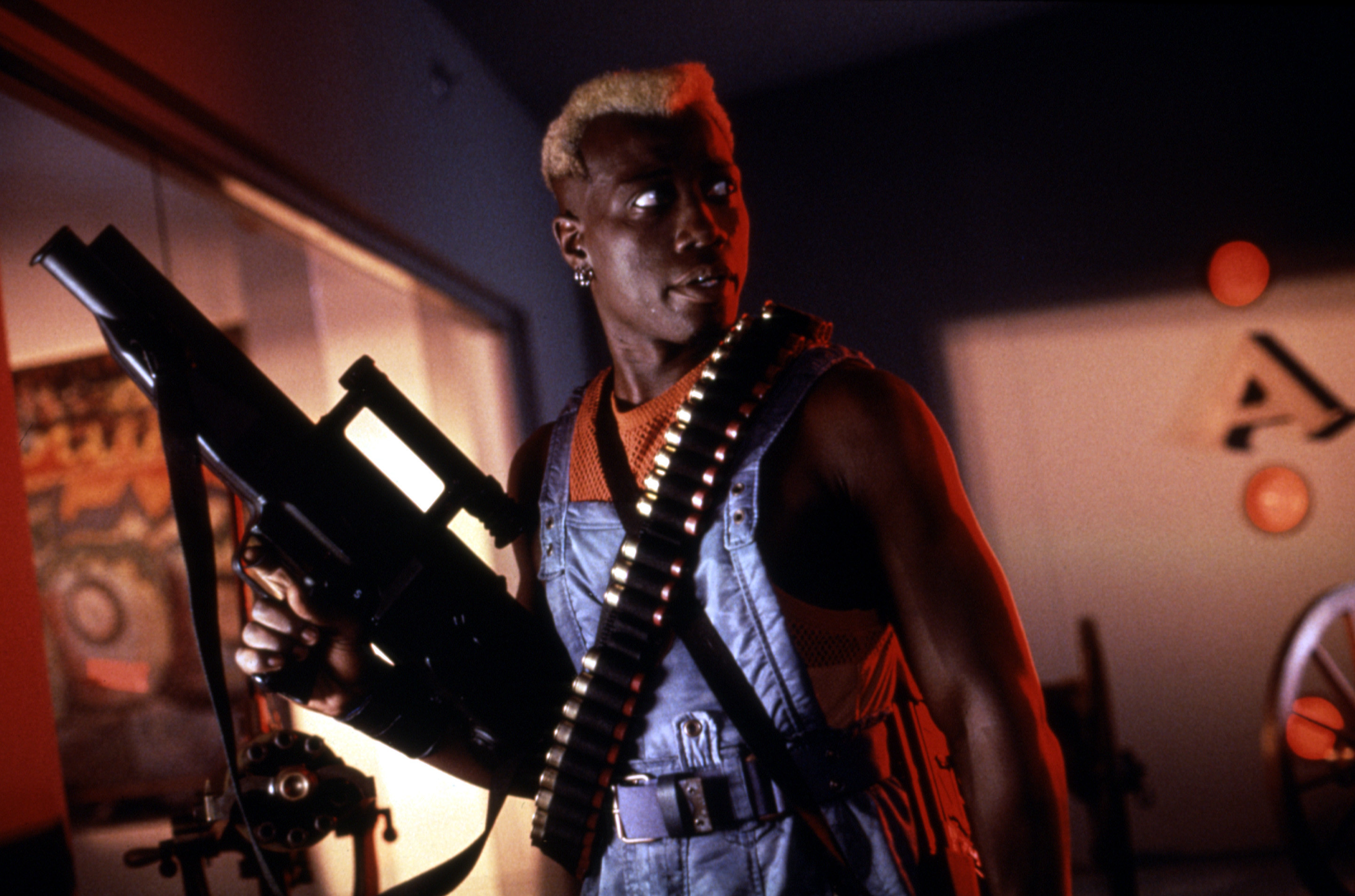 A man with bleached hair holds and massive gun