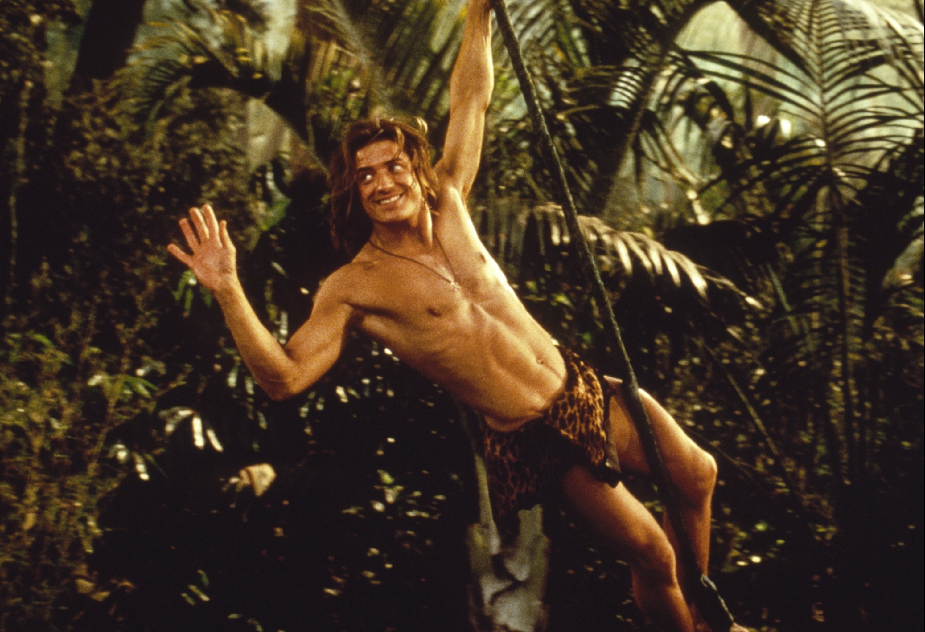 A man in a loin cloth swings through the jungle