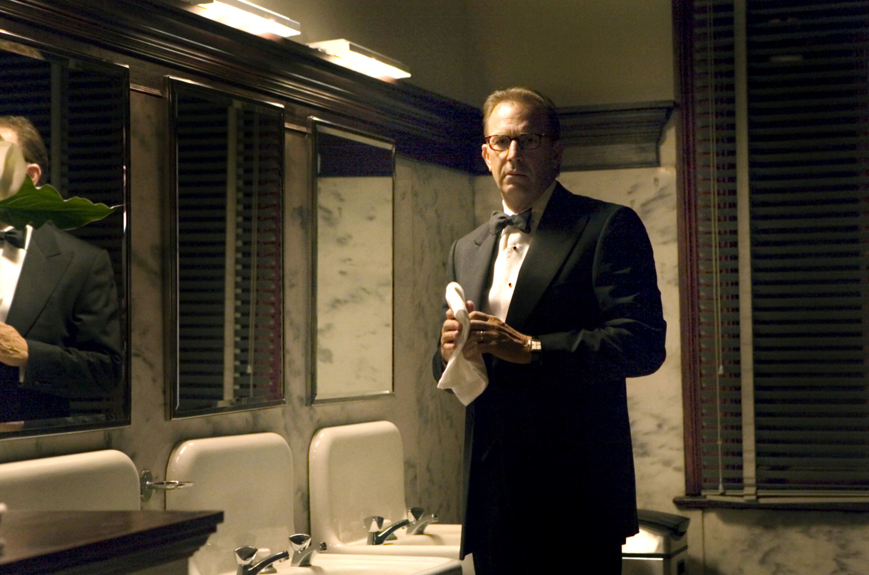 A man in a tuxedo washes his hands in a fancy bathroom