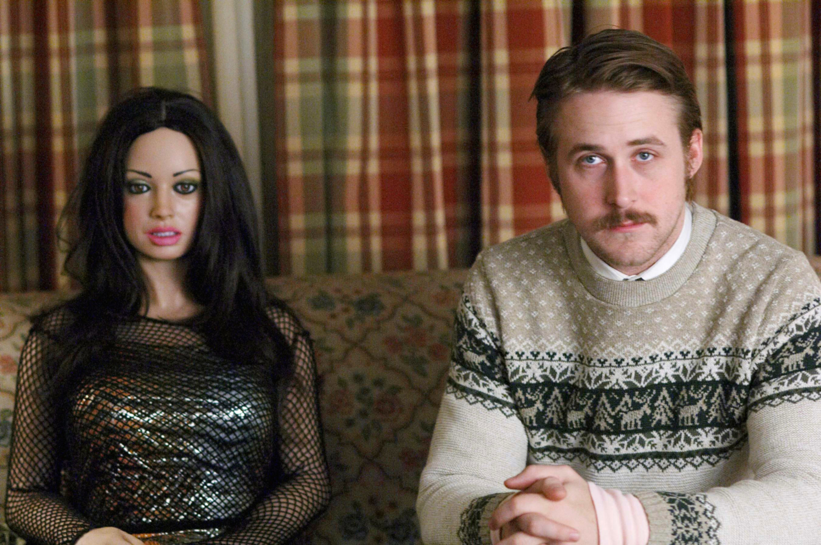 Ryan Gosling sitting next to a doll.